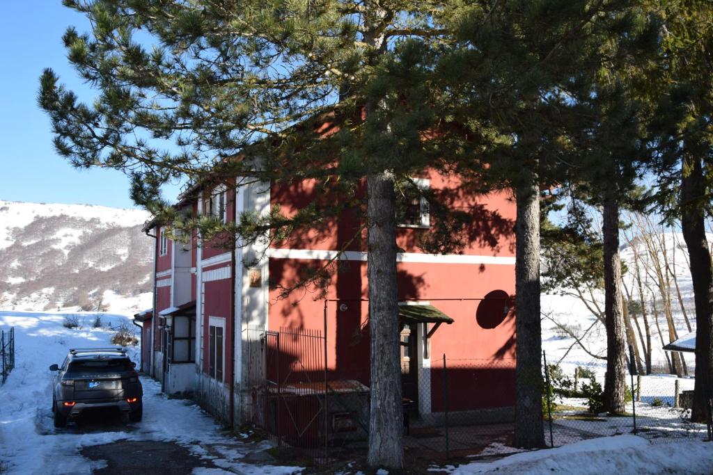 ein Auto, das neben einem roten Haus im Schnee parkt in der Unterkunft Antico Chalet Mini Momosa in Ovindoli