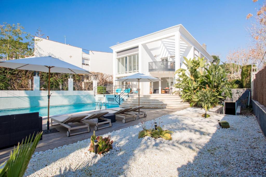 une maison avec une piscine entourée de parasols dans l'établissement Villa Cela, à El Masnou