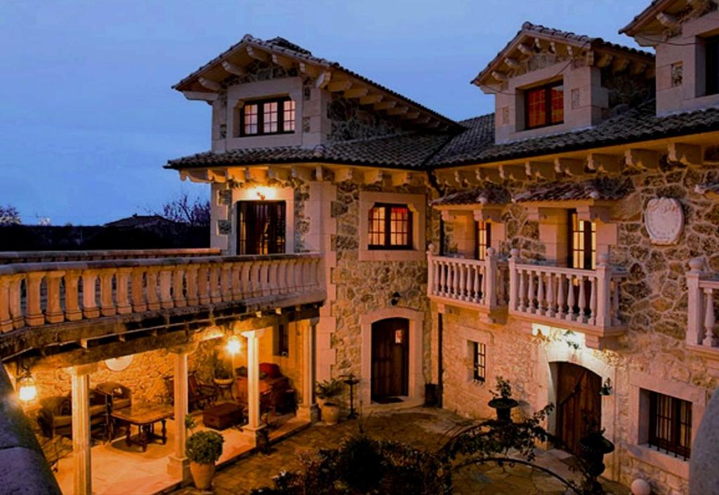 uma grande casa de pedra com uma varanda e um pátio em Hotel Rural El Cañón del Duratón em Sepúlveda