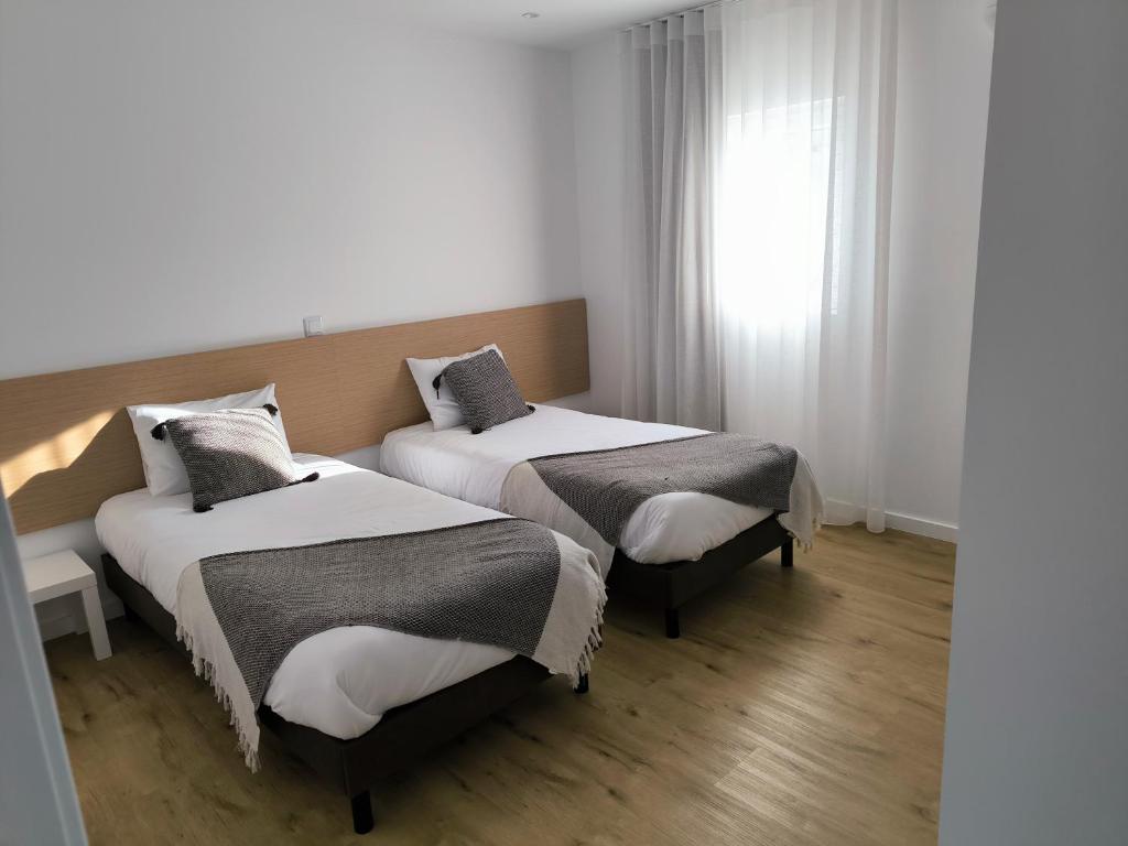 2 Betten in einem Zimmer mit Fenster in der Unterkunft Suitel Pombal in Pombal