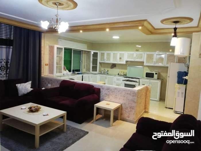 a living room with a couch and a kitchen at شقة مفروشة سكنية في مرج الحمام in Amman