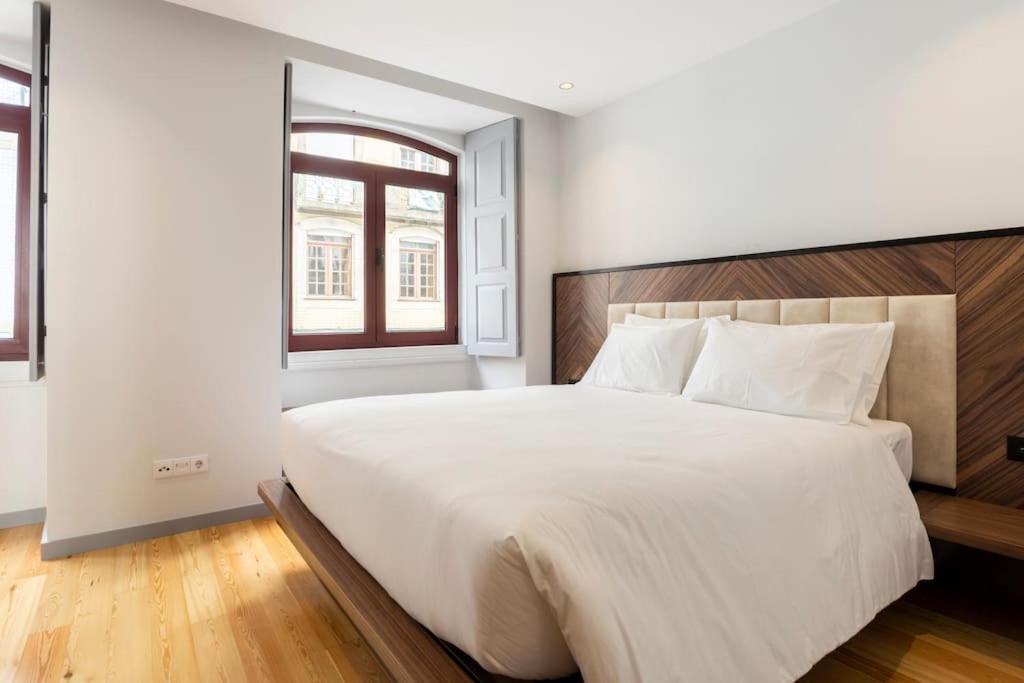 ein Schlafzimmer mit einem großen weißen Bett und einem Fenster in der Unterkunft Almada 505 City Center Duplex in Porto
