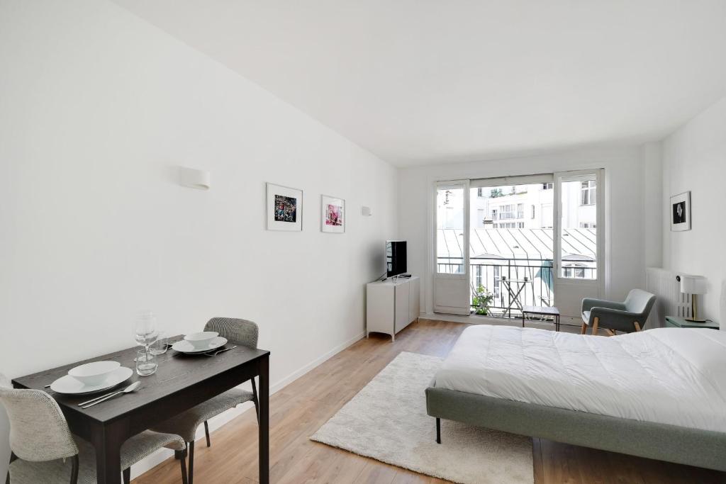 Cette chambre blanche comprend un lit et une table à manger. dans l'établissement Bright Studio for 2 - Champs-Elysées, à Paris