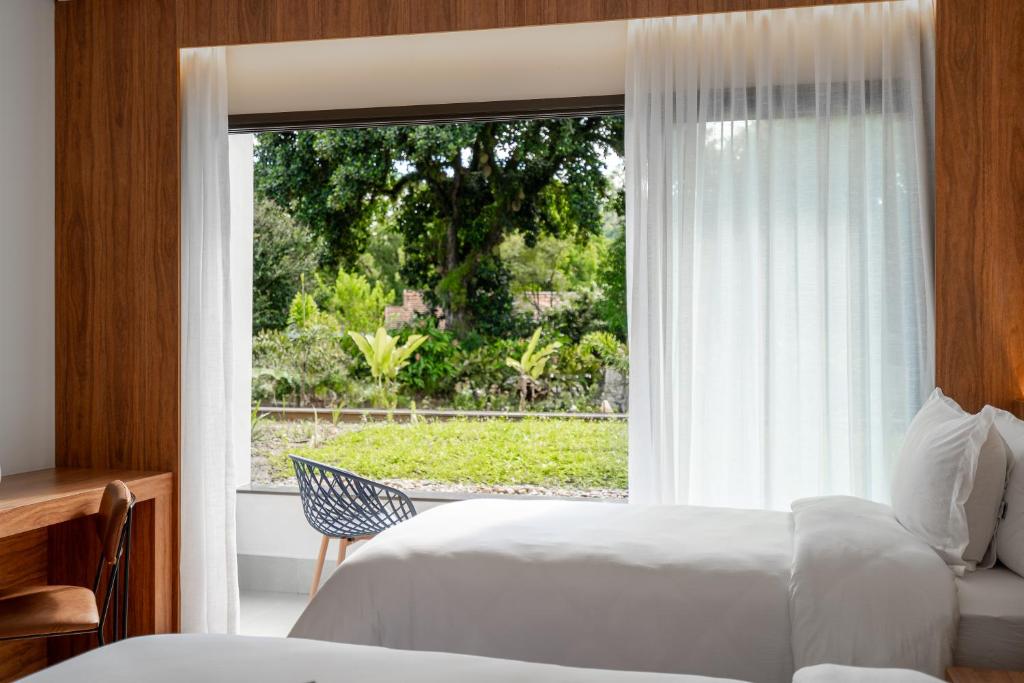 um quarto com 2 camas e uma grande janela em Vert Hotel Penedo em Penedo
