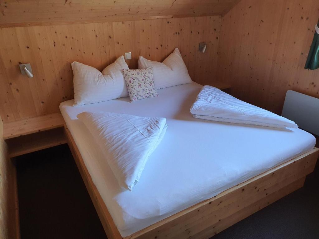 a bed in a cabin with white sheets and pillows at Exclusive chalet in Hohentauern in ski area in Hohentauern