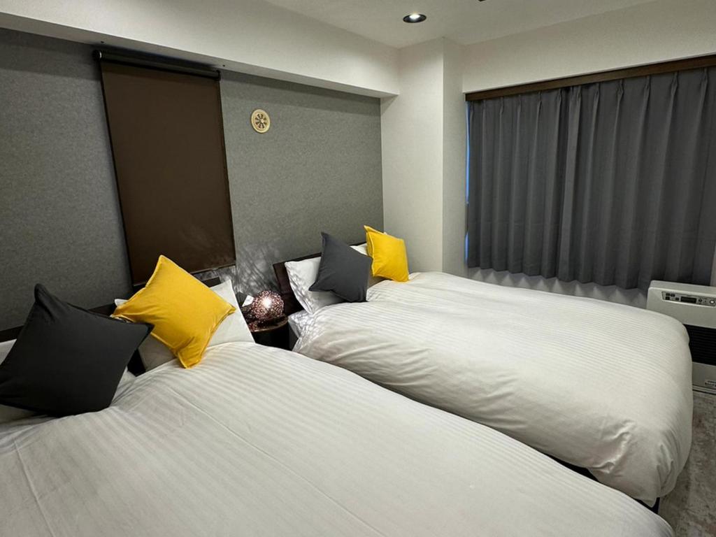 ein Hotelzimmer mit 2 Betten und gelben Kissen in der Unterkunft LIT'S INN Sapporo - Vacation STAY 47714v in Sapporo