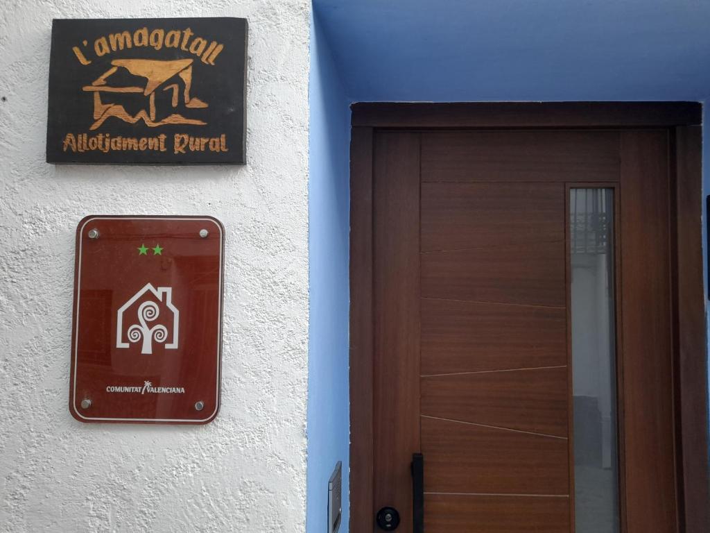 ein Schild an einem Gebäude neben einer Tür in der Unterkunft L'Amagatall in Ahín