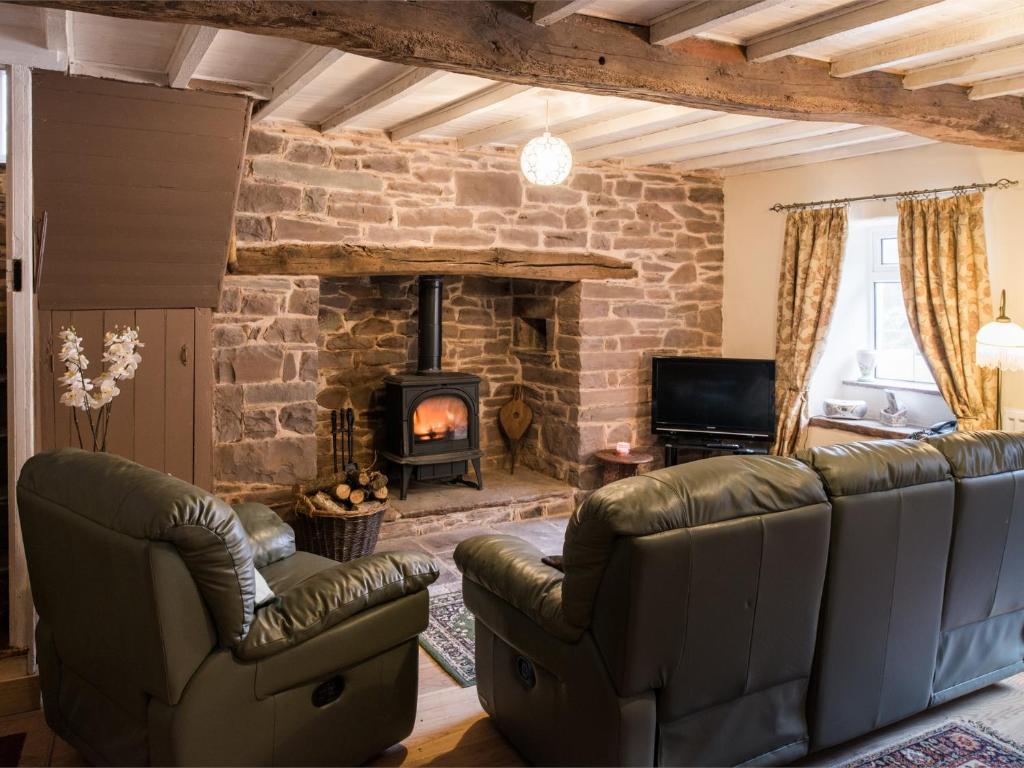 a living room with leather furniture and a stone fireplace at 2 bed in Llanfihangel-Nant-Bran BN200 in Llanfihangel-Nant-Brân