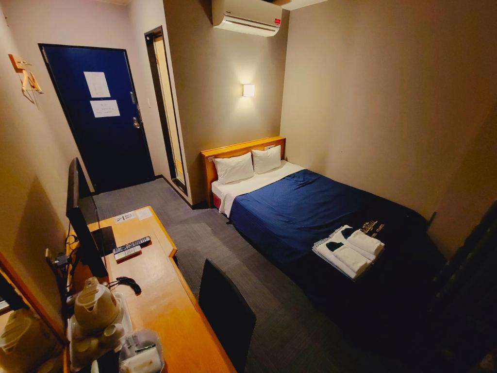 een kleine kamer met een bed en een bureau met een tafel bij HOTEL SEAGULL - Vacation STAY 36269v in Izumi-Sano