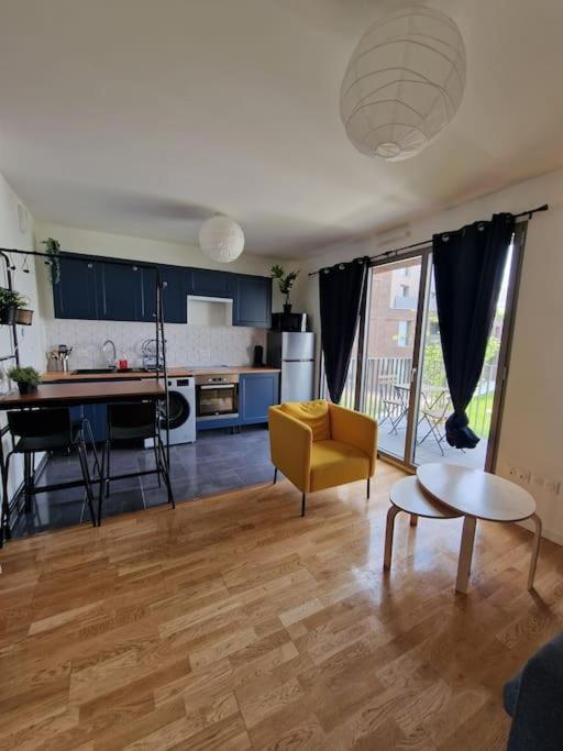 a kitchen and living room with a yellow chair and a table at Appartement neuf avec balcon/ fibre/parking privé in Massy