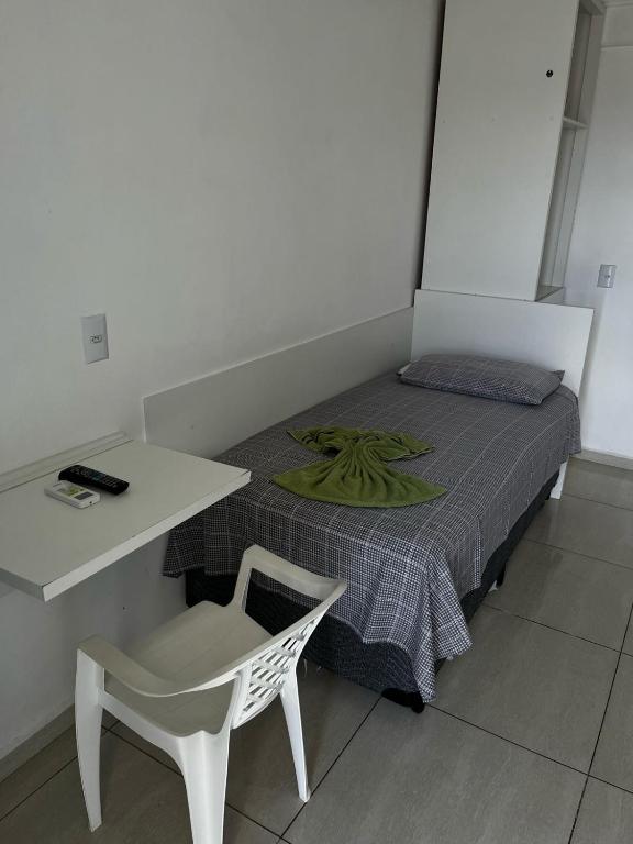 ein kleines Zimmer mit einem Bett, einem Tisch und einem Stuhl in der Unterkunft Hotel Delavy in Chapecó