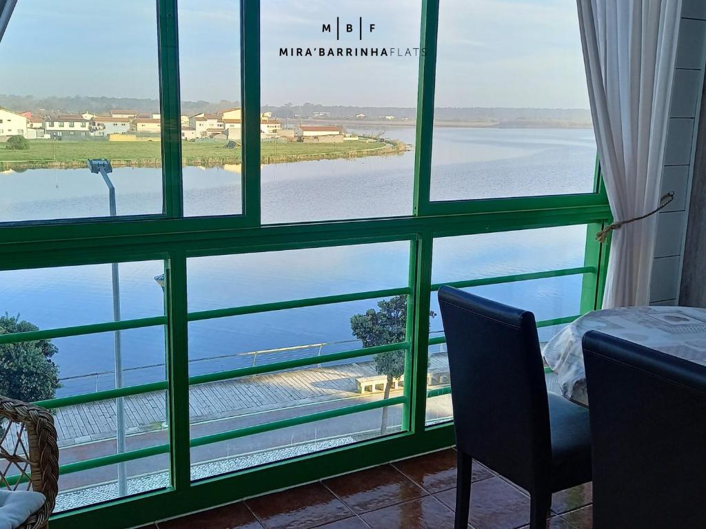a room with a large window with a view of the water at Mira'Barrinha Flats in Praia de Mira