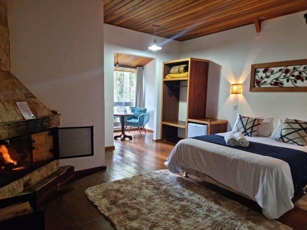 a bedroom with a large bed and a fireplace at Pousada Brisa da Mantiqueira in Monte Verde