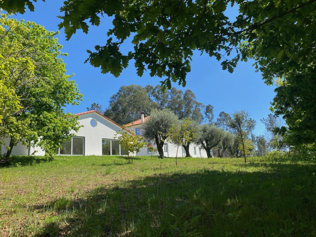 ein Haus auf einem Feld mit Bäumen im Vordergrund in der Unterkunft Catrinandes - Retreat Center in Tondela