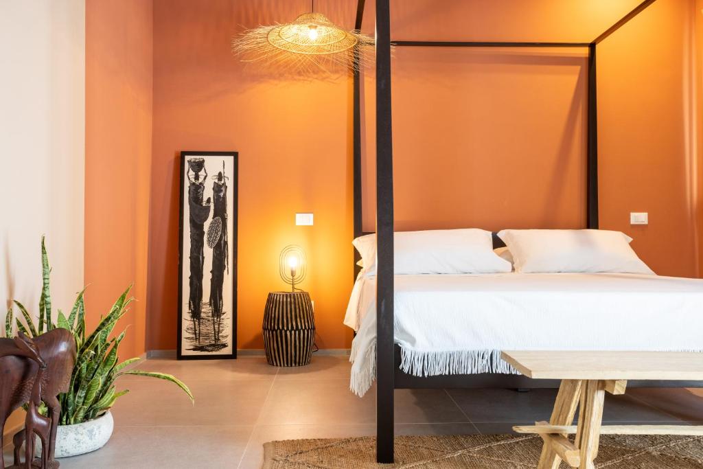 een slaapkamer met oranje muren en een bed en een tafel bij labotanica_casalounge in Cesenatico