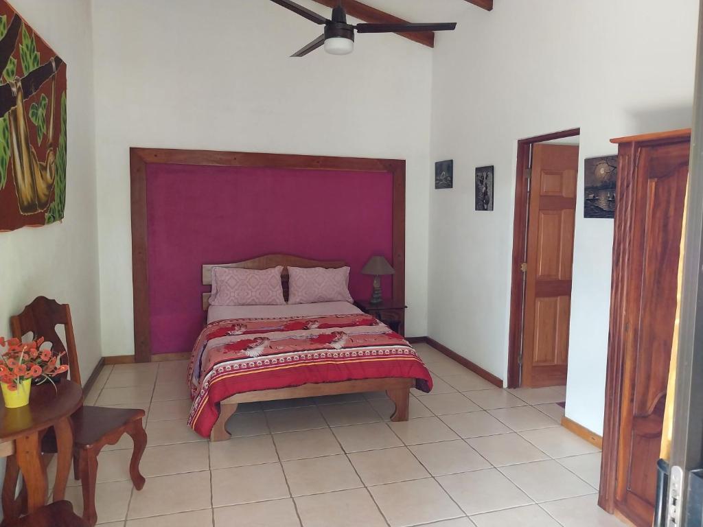 a bedroom with a bed with a purple headboard at las cabinas del sueño in Nicoya