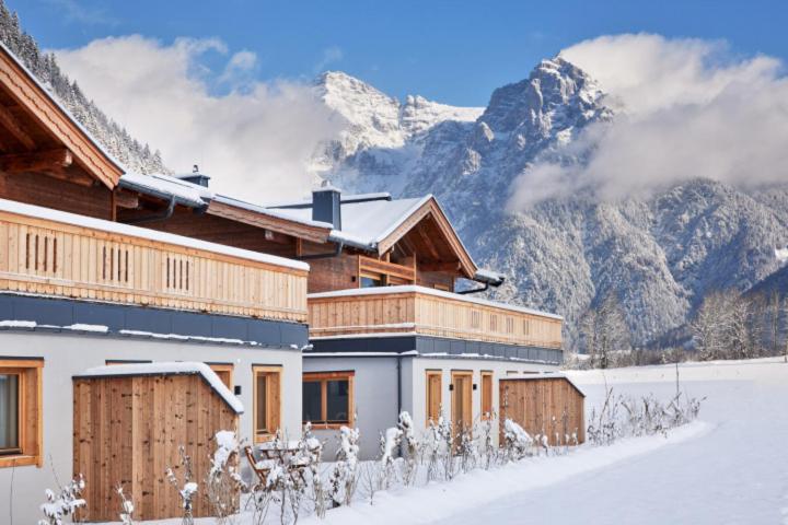 un edificio en la nieve con montañas en el fondo en Luxusapartment mit Sauna am Berg en Sankt Ulrich am Pillersee