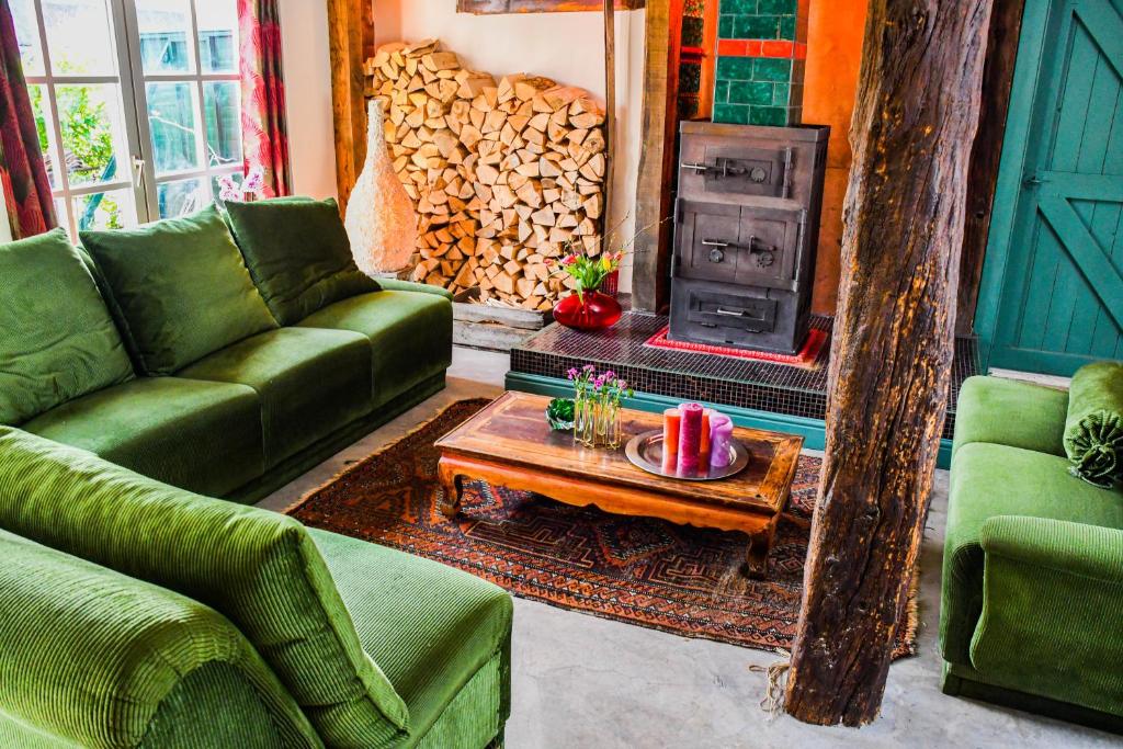 een woonkamer met groene banken en een houtkachel bij BoHo Experience Wellness, Jacuzzi, Sauna, BBQ, Garden, Sleeps 10 in Kockengen