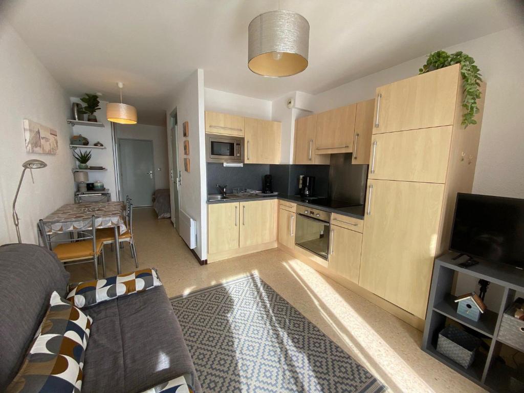 un salon avec un canapé et une cuisine dans l'établissement Appartement ⭐⭐ face à l'Étang de Thau, proche thermes, balcon et animaux bienvenus - FR-1-503-19, à Balaruc-les-Bains