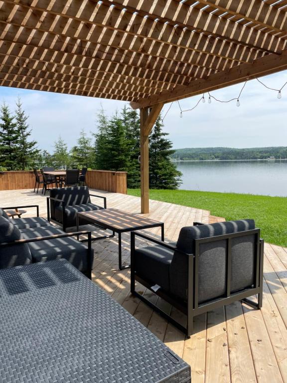 a patio with a table and chairs and a lake at Modern waterfront cottage +hot tub in Marion Bridge