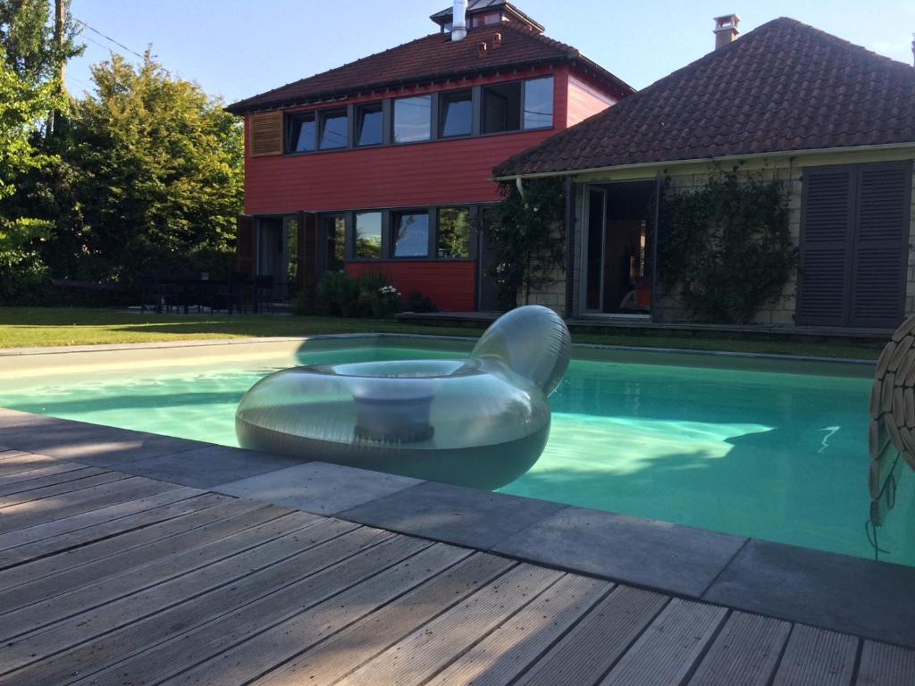 ein Schwimmbad mit einem Floß vor einem Haus in der Unterkunft Maison d'architecte idéalement située pour les JO in Neauphle-le-Château