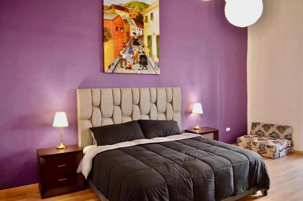 una camera con pareti viola e un grande letto di Le Chat Noir by Rotamundos a Oriental