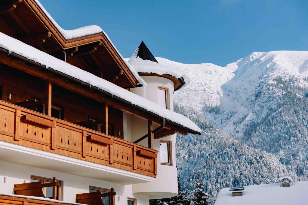 a snow covered building with a mountain in the background at loisi's Boutiquehotel in Achenkirch