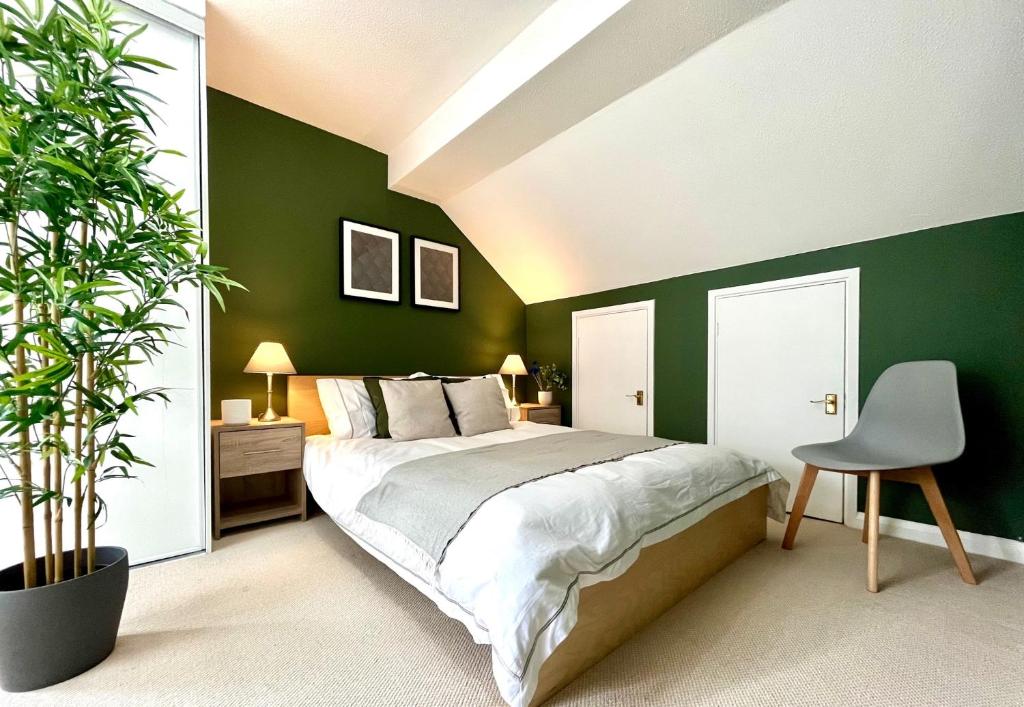 um quarto com paredes verdes e uma cama e uma cadeira em Charming home near Gatwick Airport em Crawley