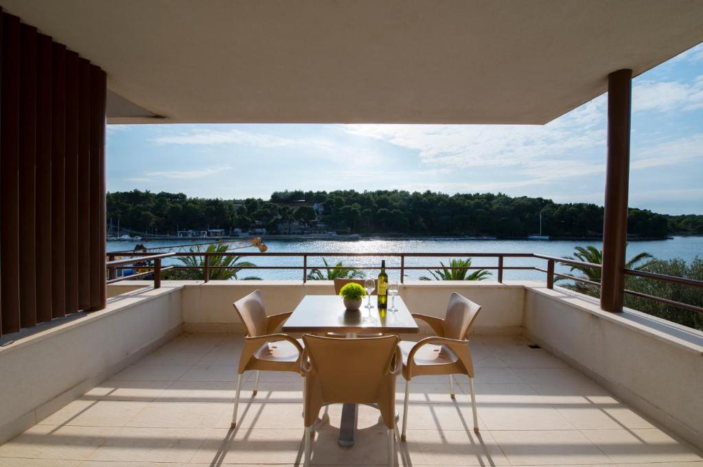 a balcony with a table and chairs and a view of the water at Moenia Apartments in Milna