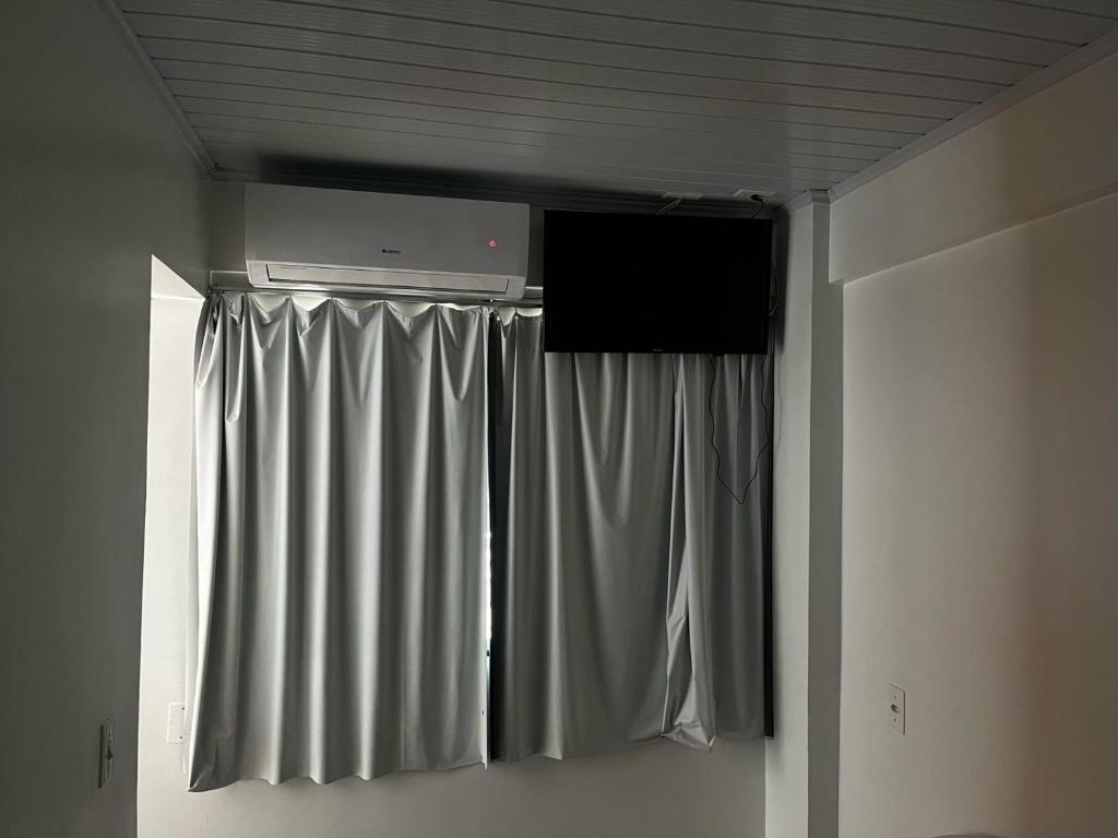 a room with a curtain and a television on the ceiling at Hotel Delavy in Chapecó