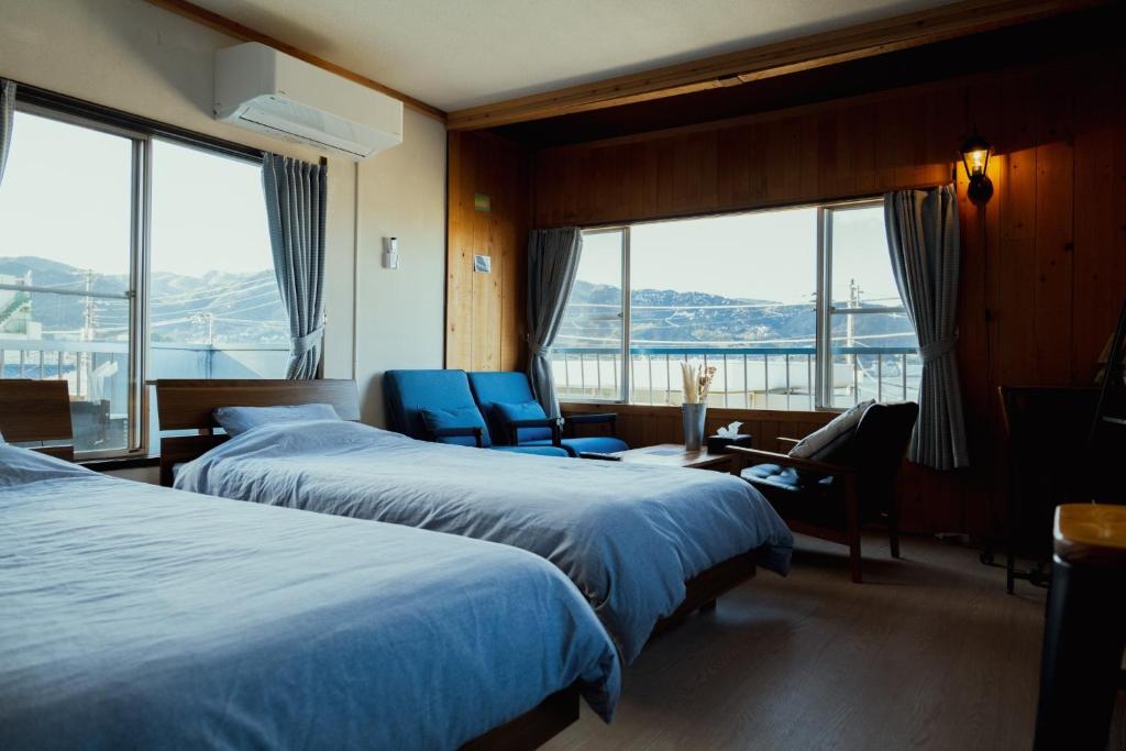 una camera d'albergo con due letti, una scrivania e sedie di Atami-Ajironokaze - Vacation STAY 87959v ad Atami