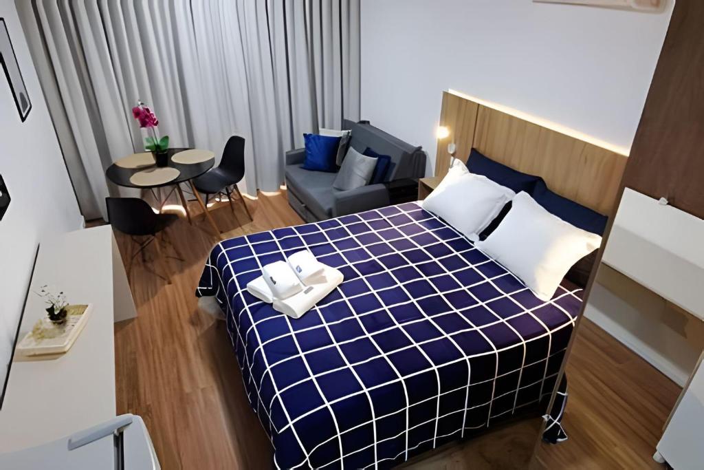 Un dormitorio con una cama azul y blanca y un sofá en Studio Pratico - Centro Poços de Caldas en Poços de Caldas