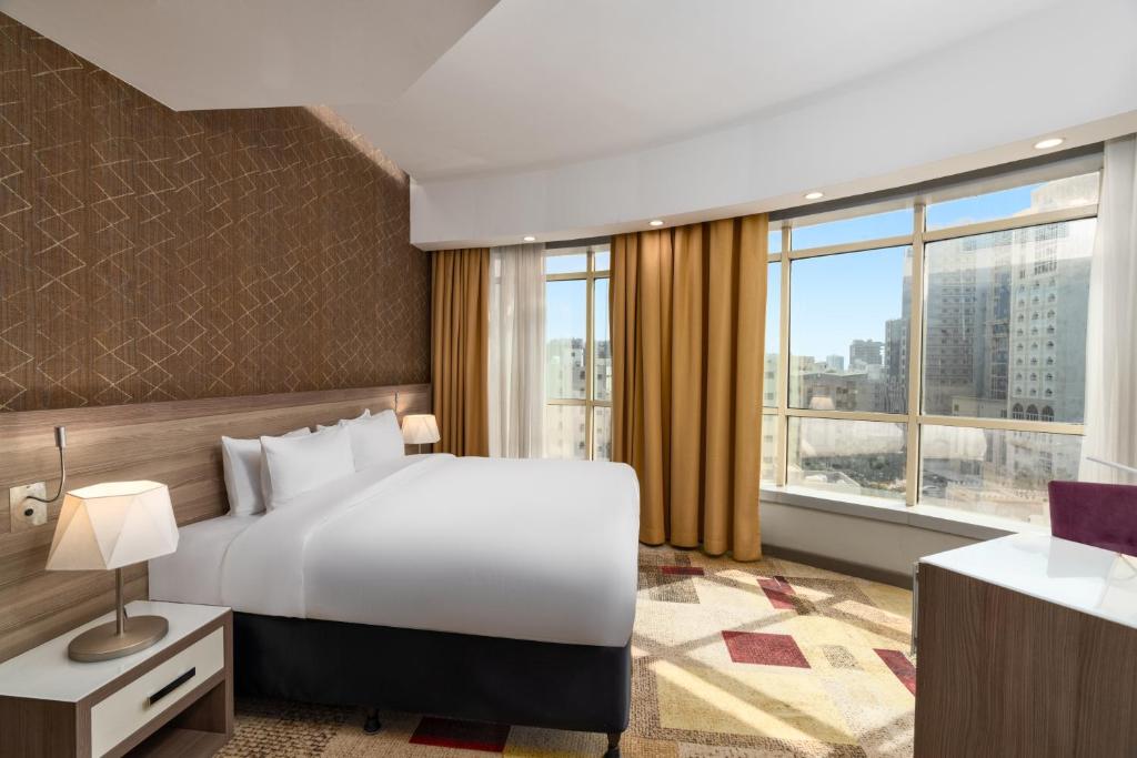 a bedroom with a large bed and a large window at Mercure Makkah Aziziah in Makkah