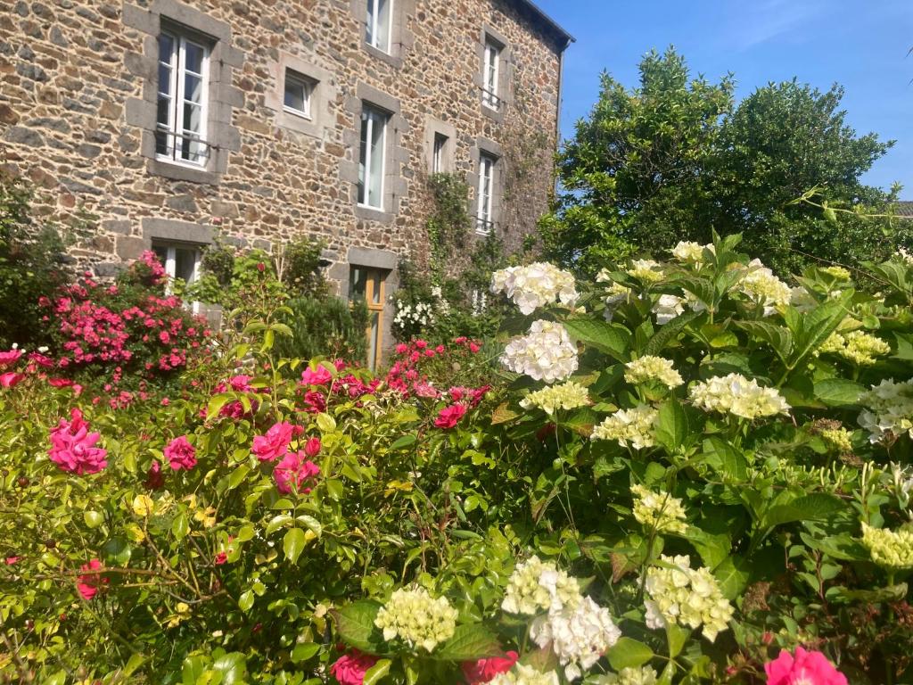 um jardim de flores em frente a um edifício de tijolos em Chambres d hôtes du Moulin à papier em Saint-Brieuc