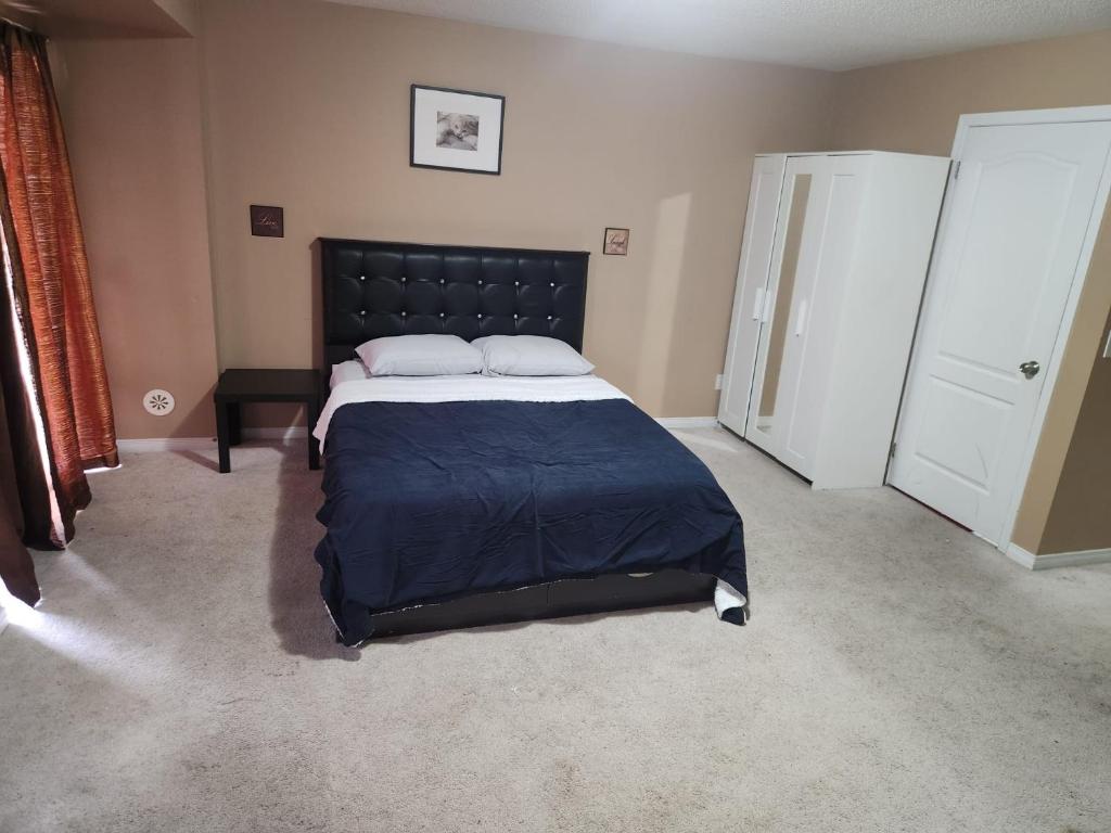 a bedroom with a large bed with a black headboard at Cozy jets empire in Brampton