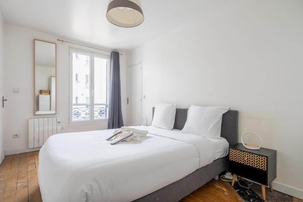 een groot wit bed in een kamer met een raam bij Loft spacieux à 10 minutes Champs-Élysées in Levallois-Perret