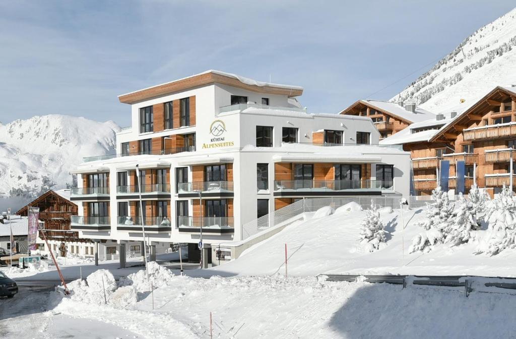 a large building in the snow with mountains in the background at Kühtai Alpensuites in Kühtai