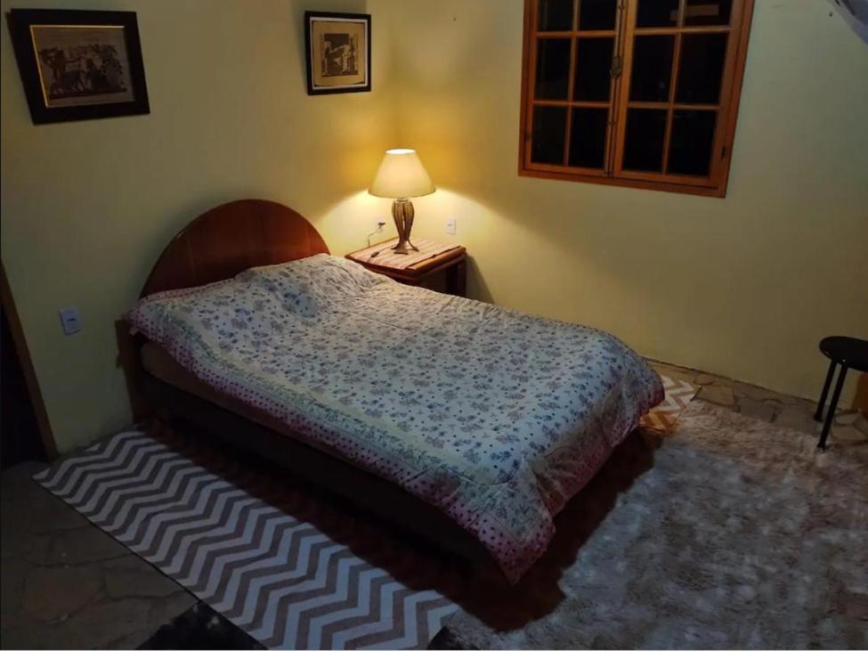 a bedroom with a bed and a lamp on a table at Fazenda e Vinícola ABN in Andrelândia