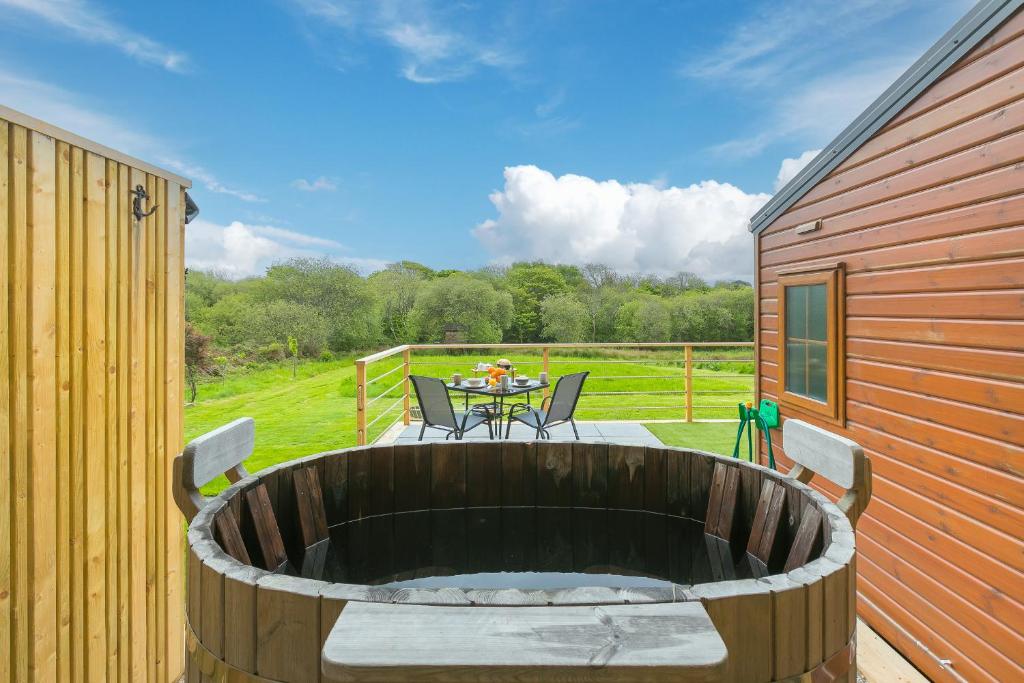 a large wooden tub sitting on a patio with a table at Lazy Lodge in Redruth
