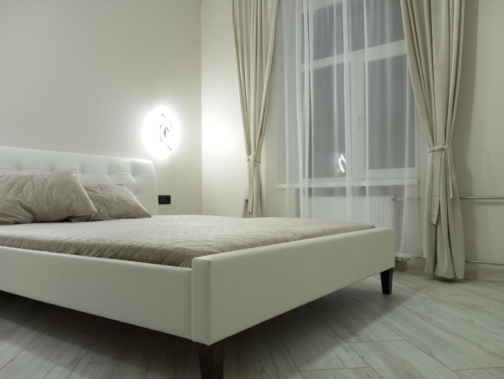 a white bed in a white bedroom with a window at Jaaniku apartment. in Ahtme