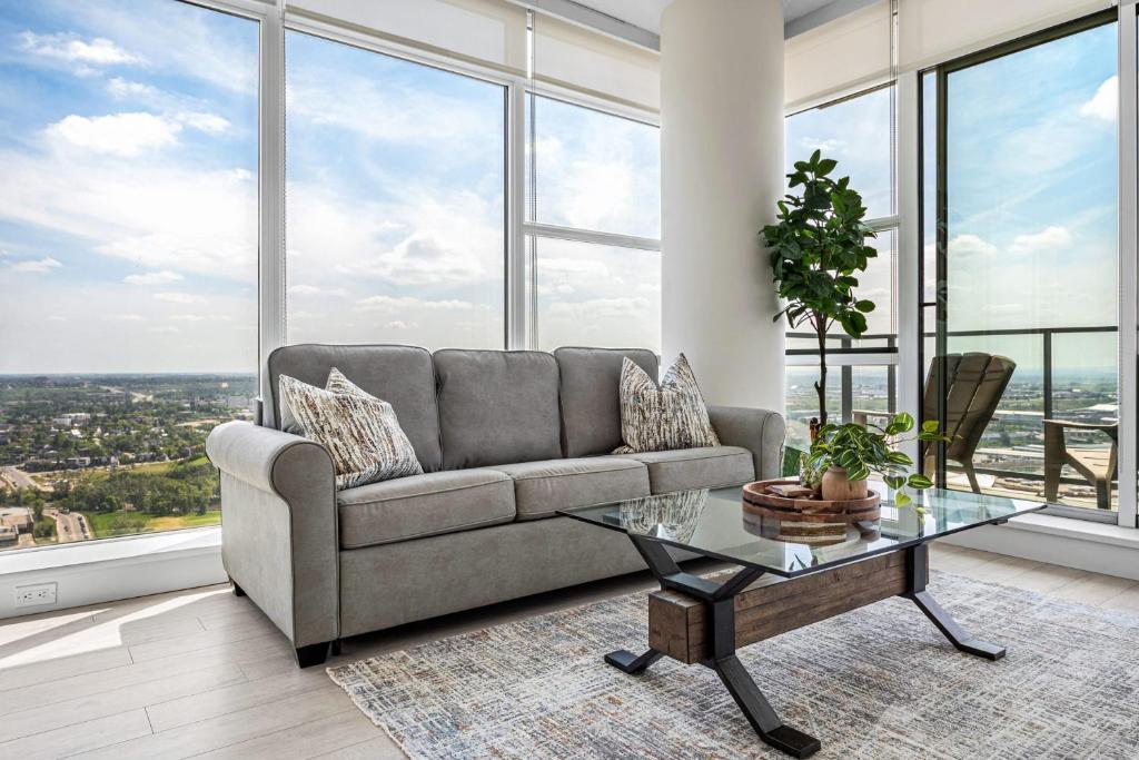 a living room with a couch and a glass table at 35th FL w the BEST Views of the Stampede & Saddledome! FREE Banff Pass, Wine, Parking & Gym! in Calgary