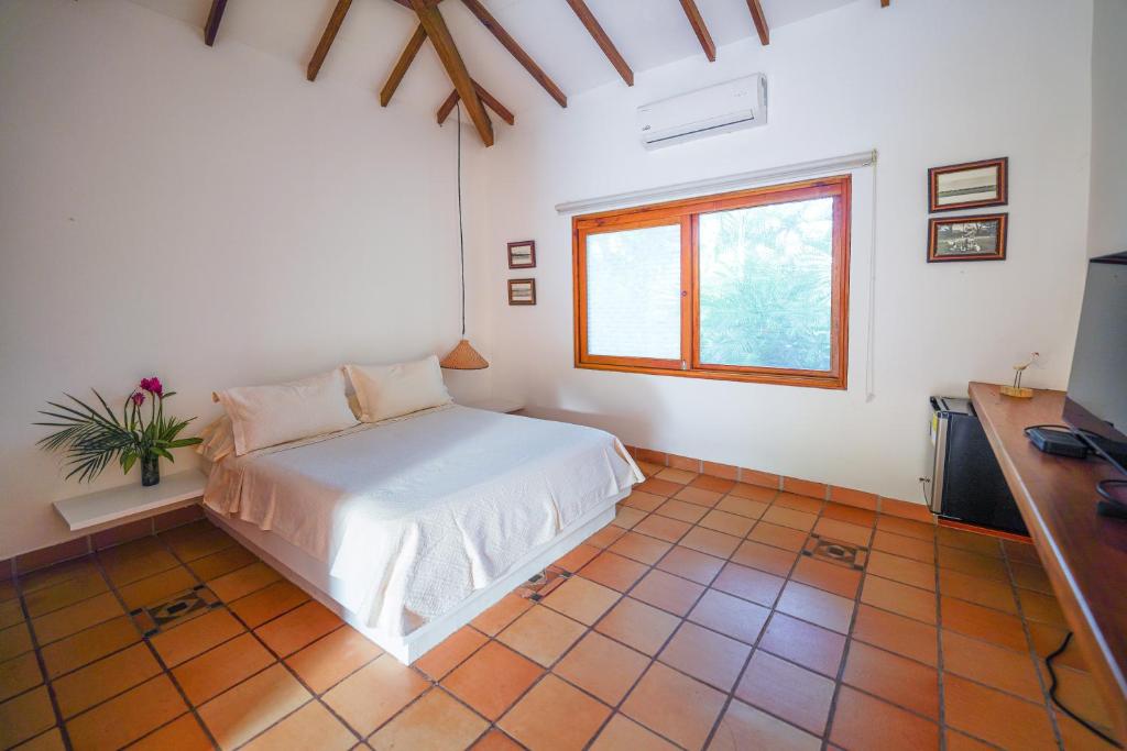 um quarto com uma cama branca e uma janela em Casa Cumbres Ecolodge em Yopal