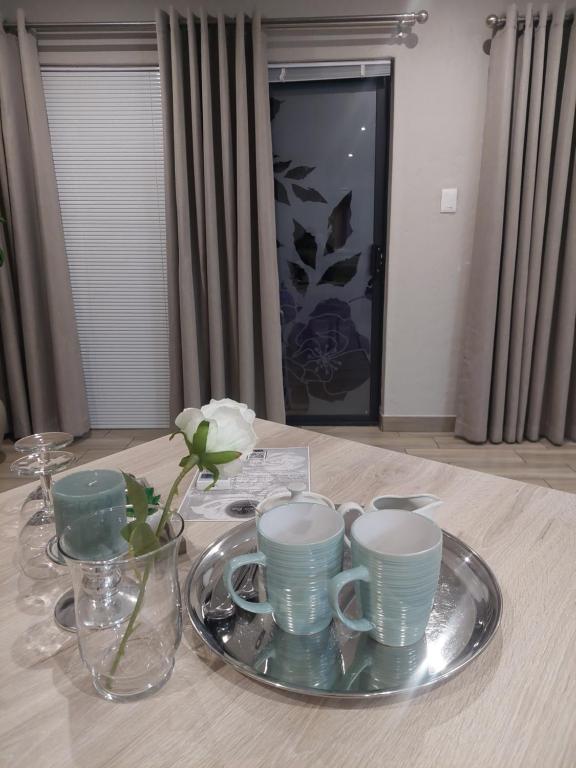 a table with a plate with cups and vases on it at Bella Rosa in Potchefstroom