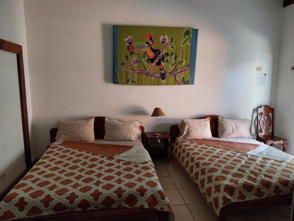 two beds in a room with a painting on the wall at Las cabinas del sueño in Nicoya