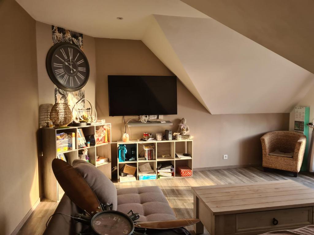 sala de estar con sofá y reloj en la pared en chambre à louer, en Magny-en-Bessin