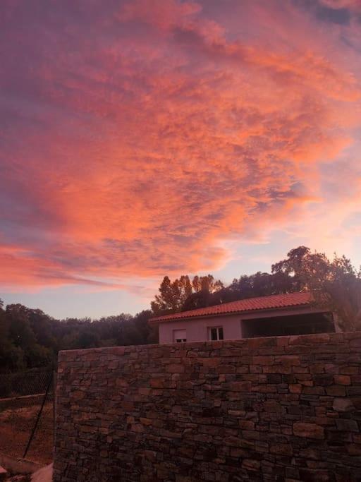 un coucher de soleil sur un mur de briques et un bâtiment dans l'établissement Casa di l Alivetu, à Ventiseri