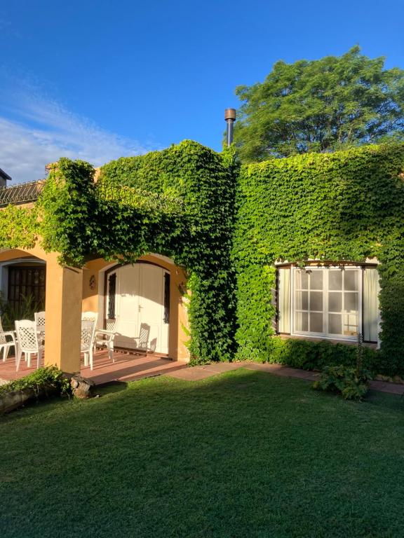 a house covered in green ivy with a yard at La Madreselva in San Antonio de Areco