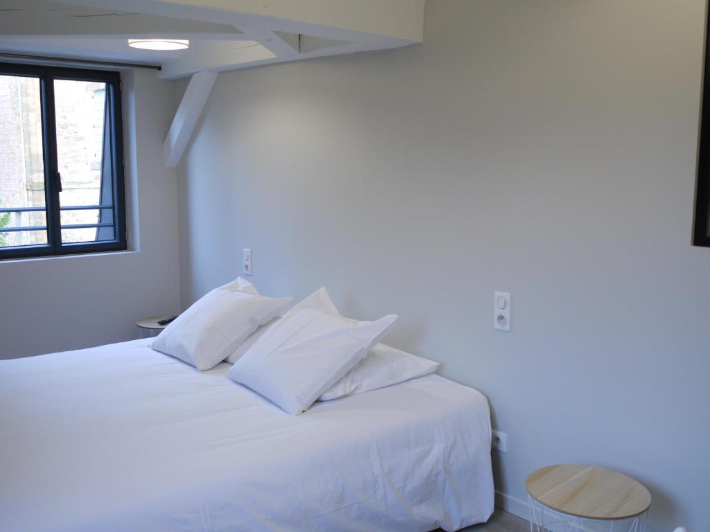 a white bed with white pillows in a bedroom at Le Trèfle à Quatre Feuilles in Siorac-en-Périgord