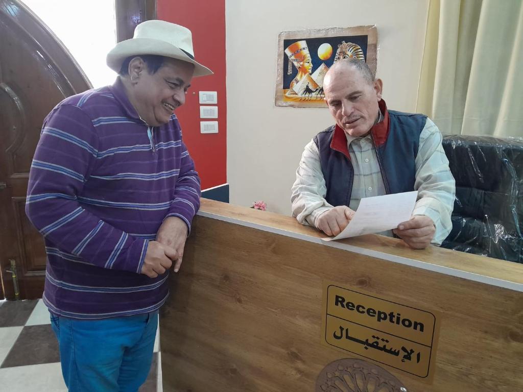 an older man is looking at a paper at a counter at فندق لؤلؤة الريف in Kafr ʼakīm