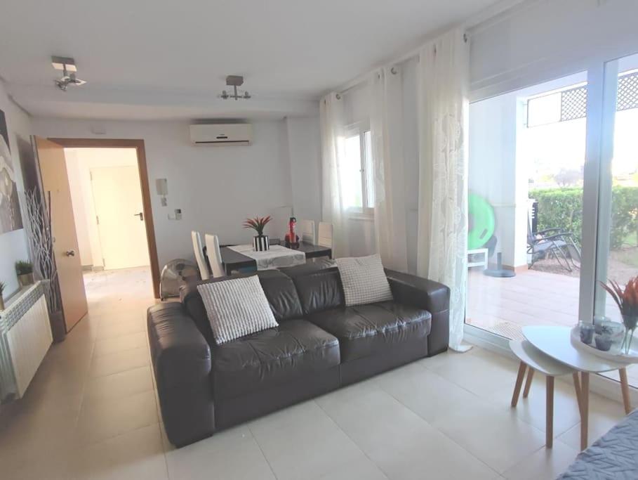 a living room with a black couch and a table at Hacienda Riquelme Golf Resort Ground Floor Apartment Sucina Murcia in Murcia